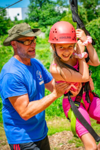 Camp staff helping camper with rope climbing